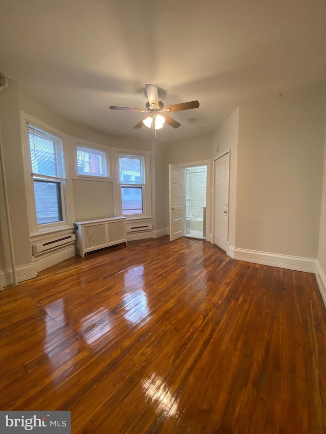 spare room with dark wood-type flooring, baseboard heating, and ceiling fan