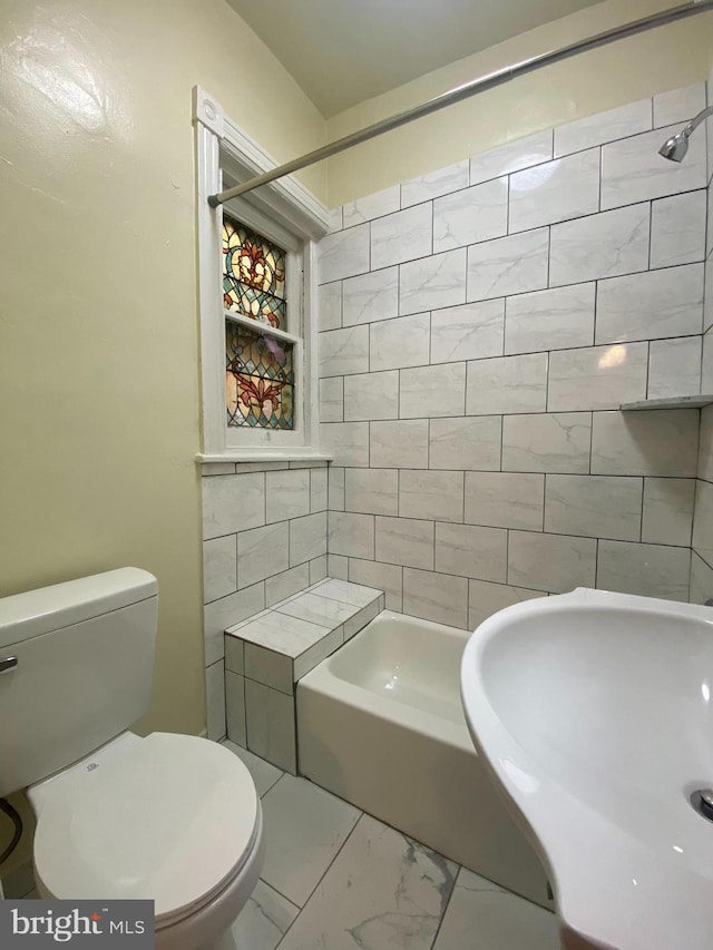 full bathroom with tiled shower / bath combo, toilet, and sink