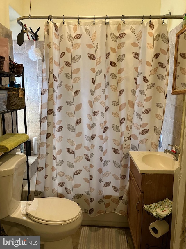 bathroom with vanity, toilet, a shower with curtain, and tile walls