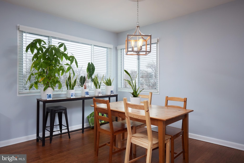 dining area with baseboards, dark wood finished floors, and an inviting chandelier