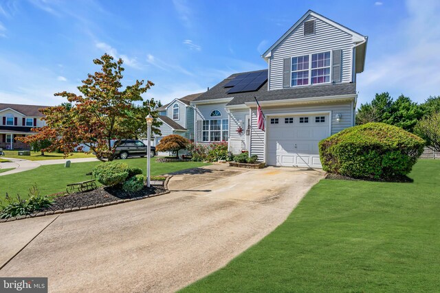 front of property with a garage, solar panels, and a front yard