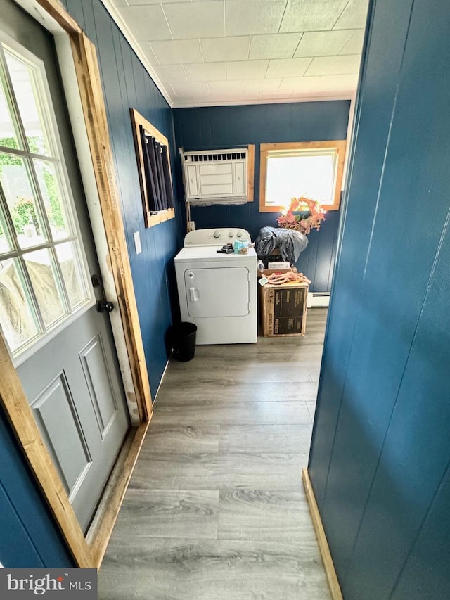 washroom featuring a healthy amount of sunlight, wood-type flooring, washer / dryer, and cabinets