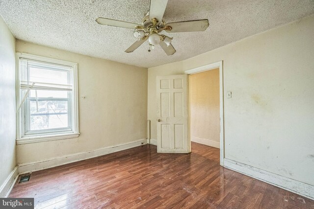 unfurnished bedroom with a textured ceiling, ceiling fan, and dark hardwood / wood-style flooring