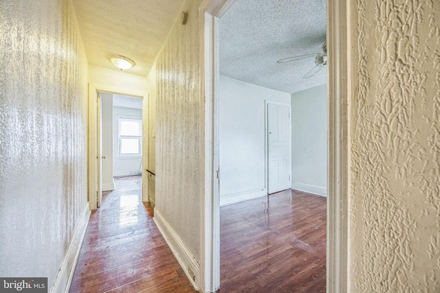 corridor with wood-type flooring and a textured ceiling