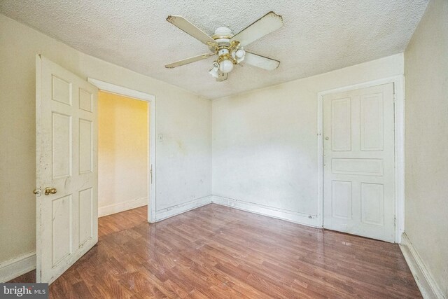 unfurnished room featuring a textured ceiling, wood-type flooring, and ceiling fan