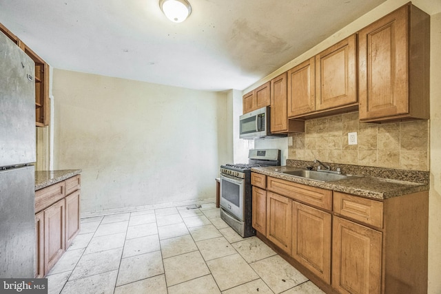 kitchen with dark stone counters, light tile patterned floors, sink, decorative backsplash, and appliances with stainless steel finishes