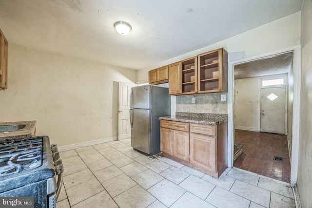 kitchen with range with gas stovetop, light tile patterned floors, and stainless steel refrigerator