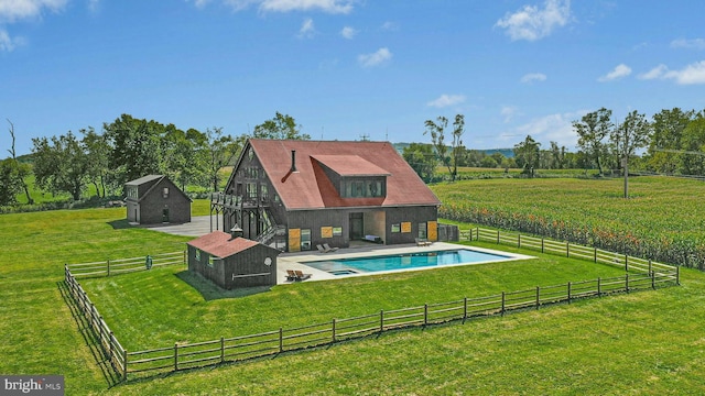 view of swimming pool featuring a yard, an outbuilding, and a rural view