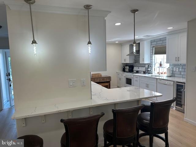 kitchen featuring a kitchen breakfast bar, hanging light fixtures, white cabinetry, kitchen peninsula, and light wood-type flooring