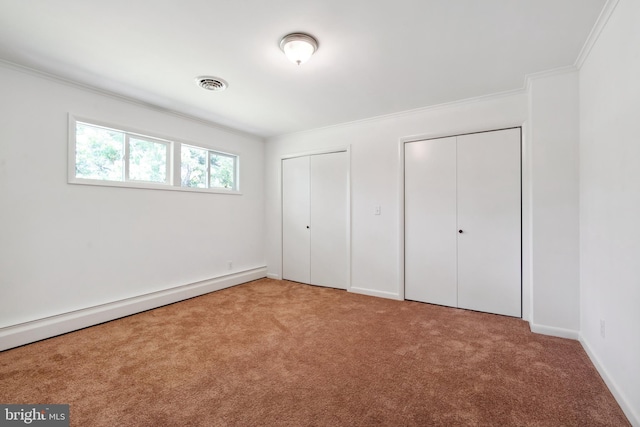 unfurnished bedroom featuring crown molding, carpet, multiple closets, and a baseboard radiator