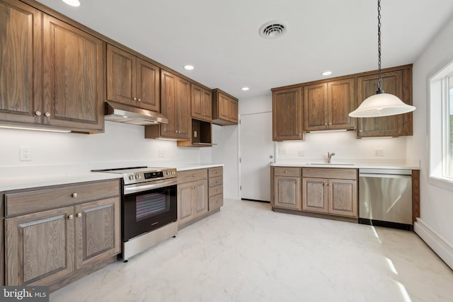 kitchen featuring decorative light fixtures, stainless steel appliances, baseboard heating, and sink