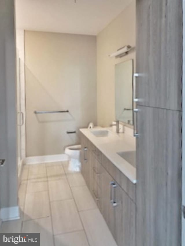 bathroom with tile patterned floors, a shower with shower door, toilet, and vanity