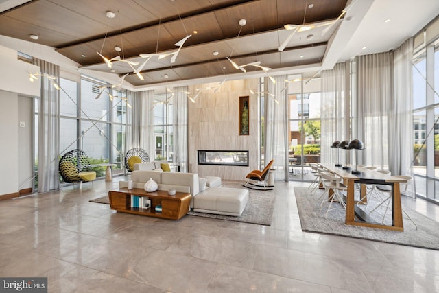 living room featuring floor to ceiling windows, a tiled fireplace, and wooden ceiling