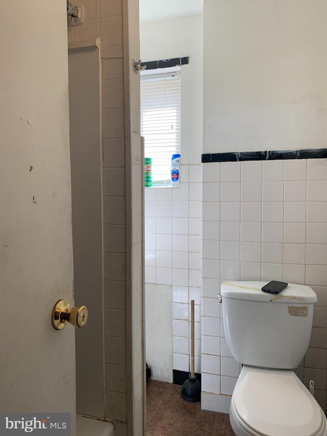 bathroom featuring tile walls and toilet