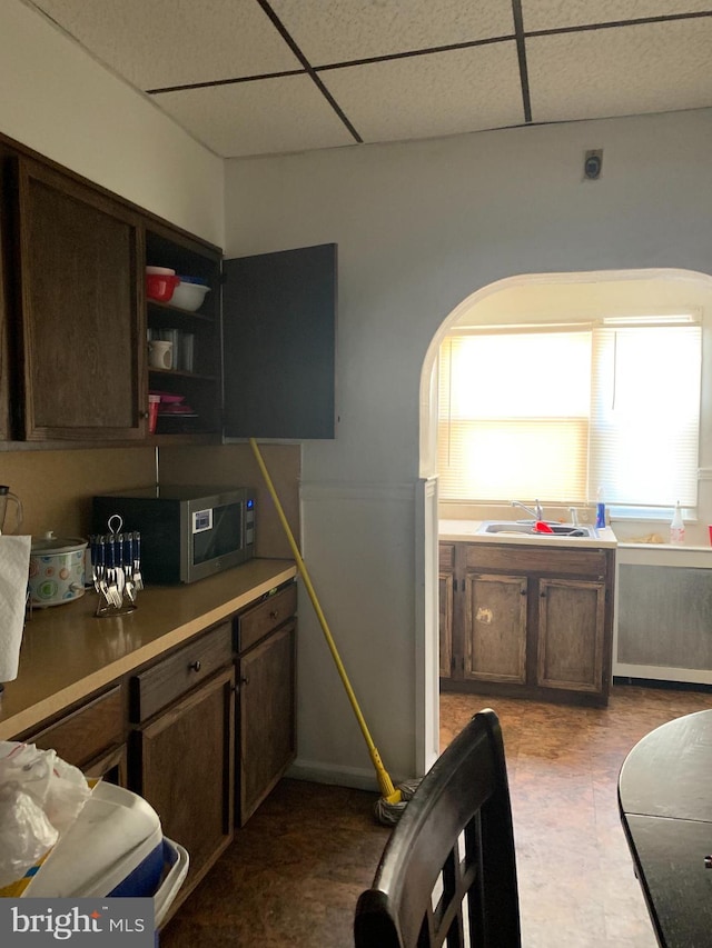 kitchen with dark brown cabinetry, a paneled ceiling, and sink