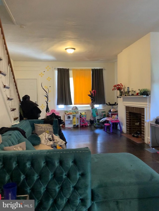 living room featuring a brick fireplace and dark wood-type flooring