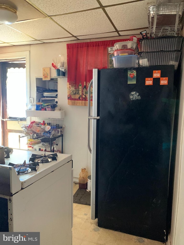 kitchen featuring a drop ceiling, black fridge, and washer / dryer