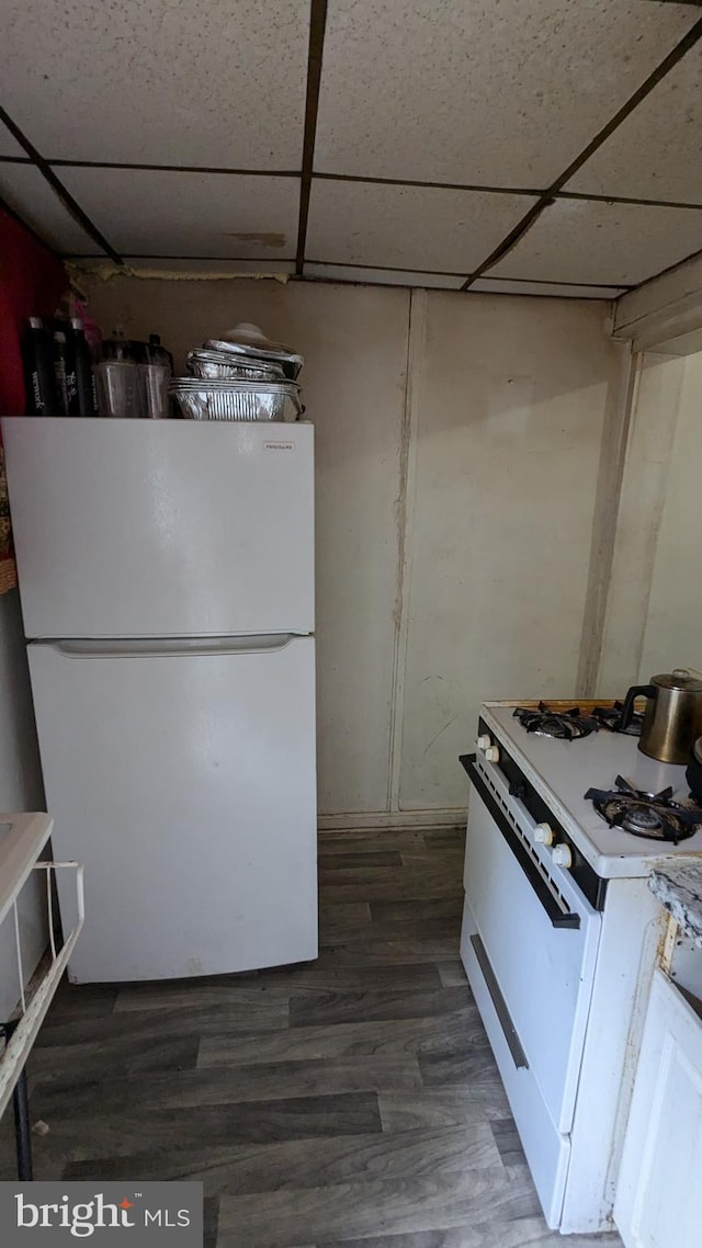 kitchen with a paneled ceiling, white appliances, and dark wood-type flooring