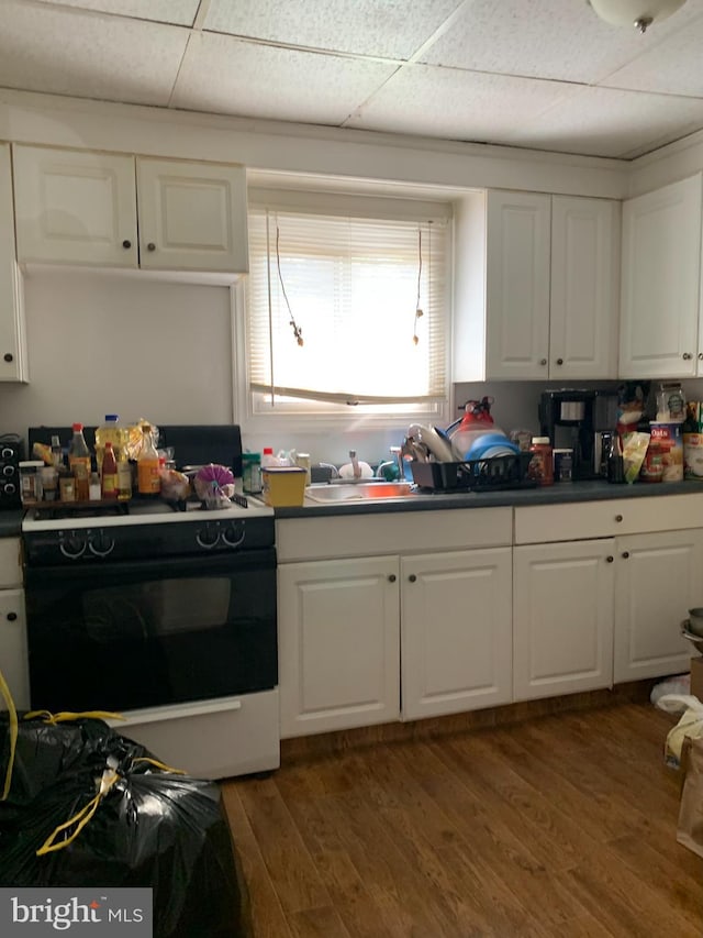 kitchen featuring wood-type flooring, white cabinetry, white range with electric stovetop, and a paneled ceiling