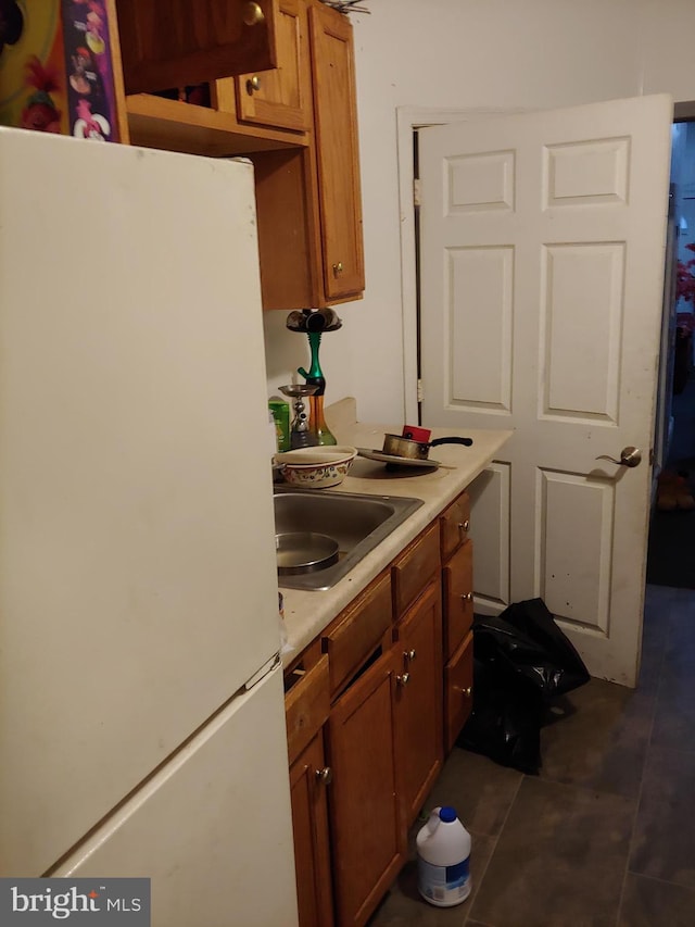 kitchen featuring dark tile patterned floors, white fridge, and sink