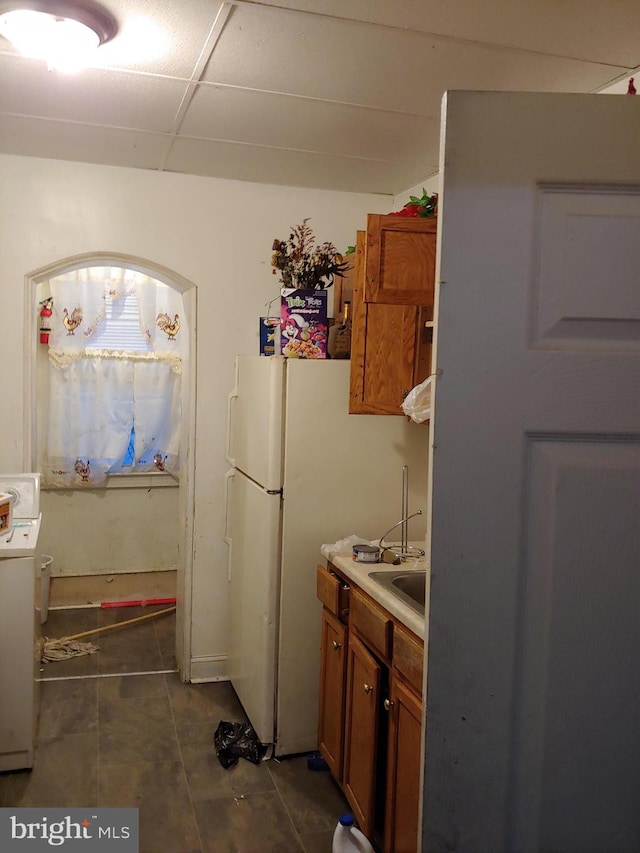 kitchen featuring washer / dryer, dark tile patterned flooring, and white fridge