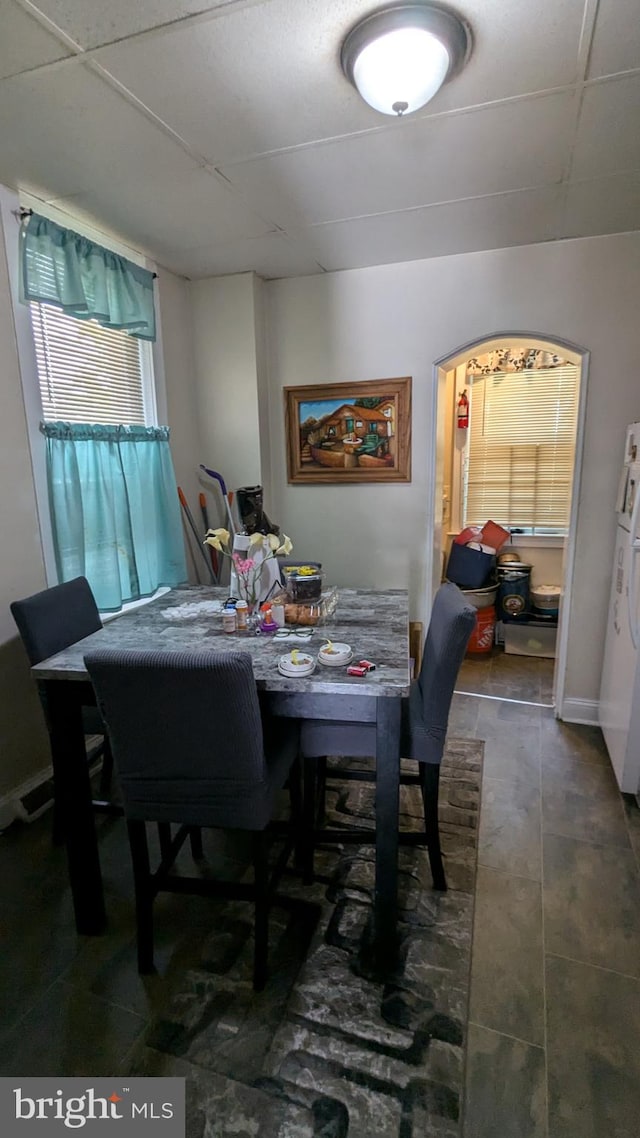 dining area featuring dark tile patterned flooring and a paneled ceiling