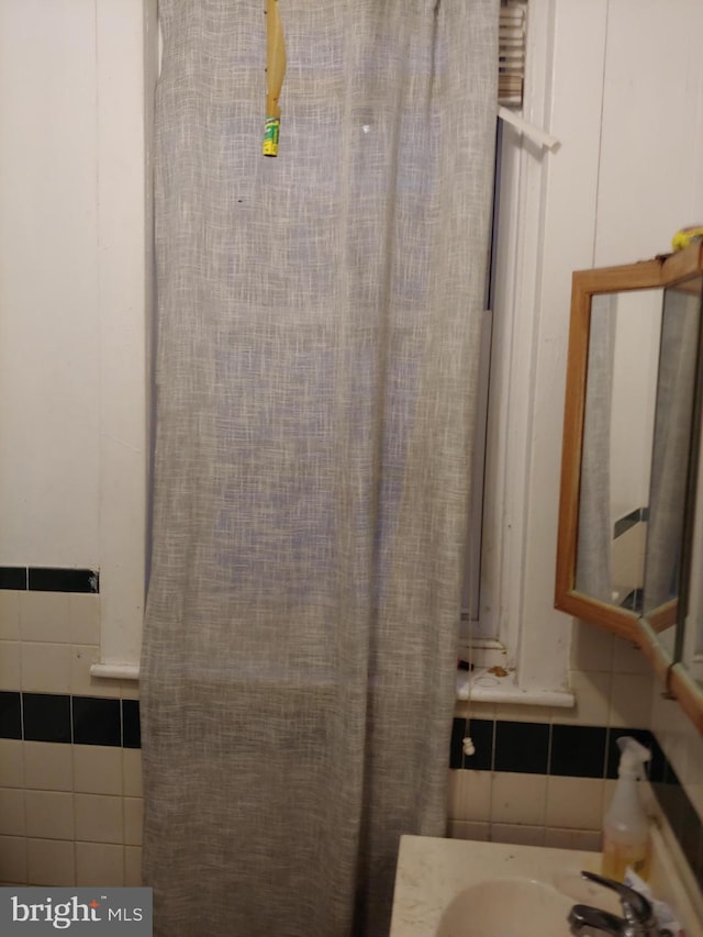 bathroom featuring tile walls and sink