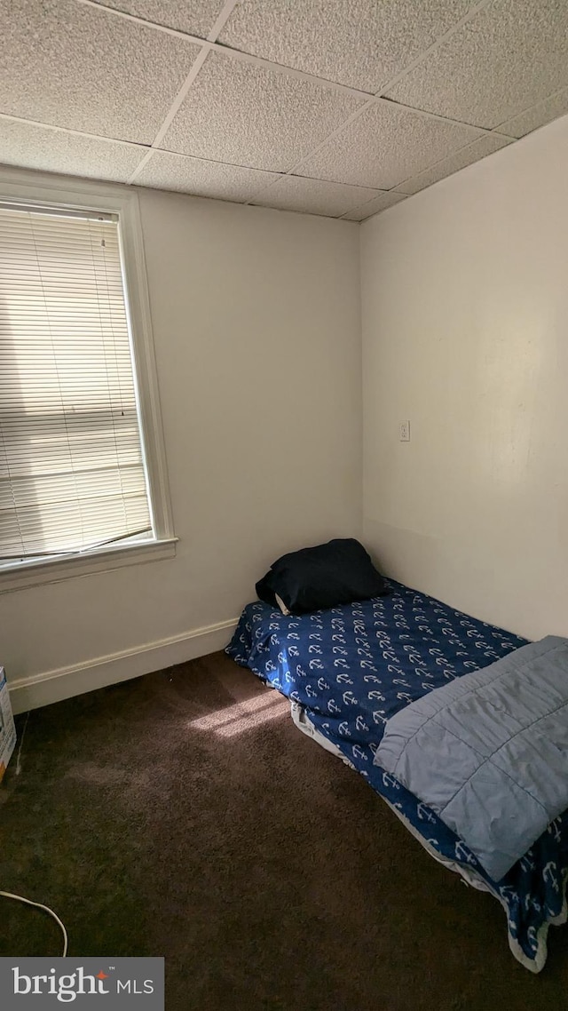 carpeted bedroom featuring a drop ceiling