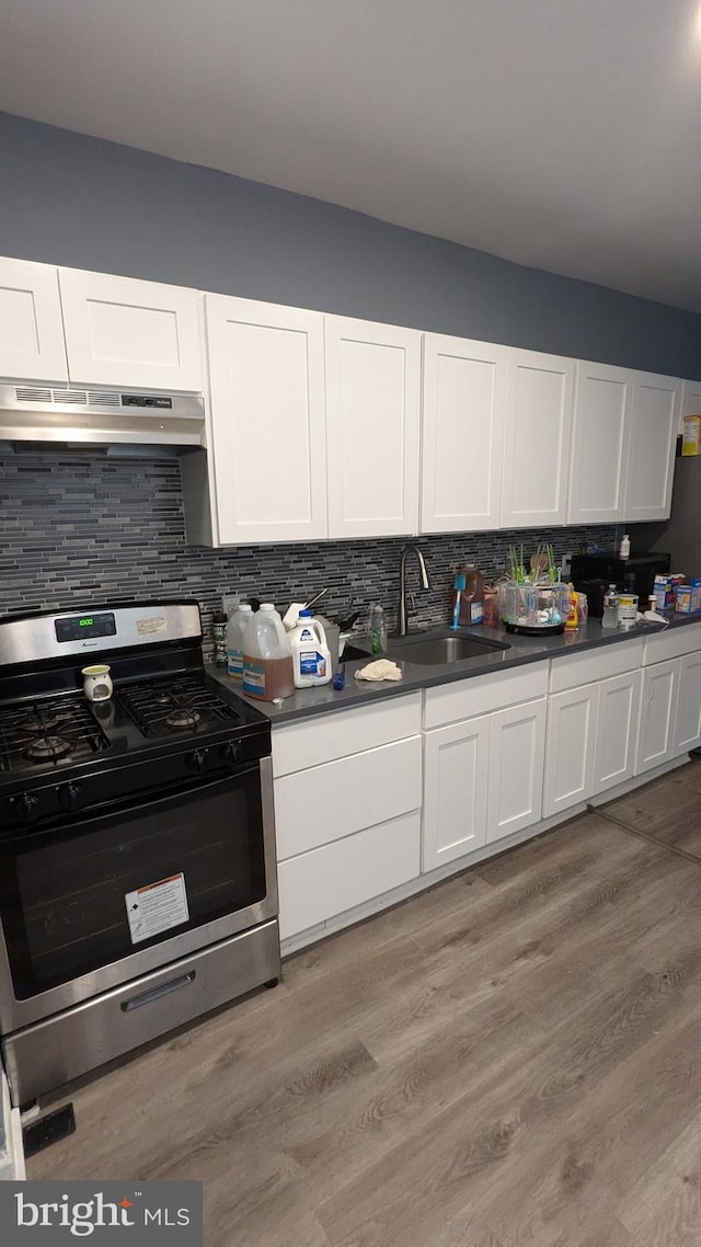 kitchen with light hardwood / wood-style floors, sink, white cabinetry, decorative backsplash, and stainless steel range