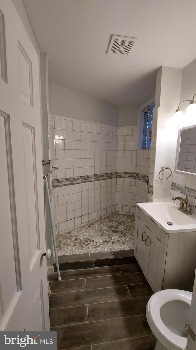 bathroom with tiled shower and vanity