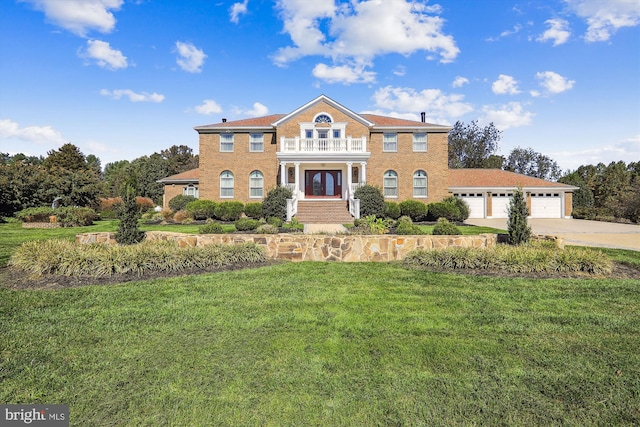 view of front facade featuring a front yard, a balcony, and a garage