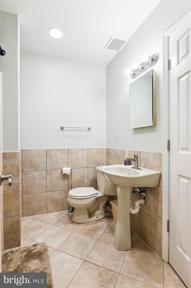 bathroom with tile walls, tile patterned floors, and toilet