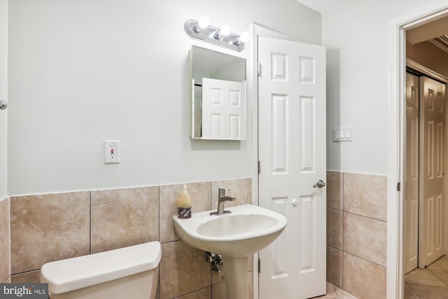 bathroom with tile patterned flooring, tile walls, sink, and toilet