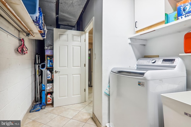 clothes washing area with washer / clothes dryer, cabinets, sink, and light tile patterned floors