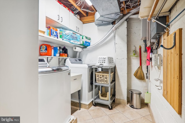 washroom featuring separate washer and dryer, cabinets, and light tile patterned floors