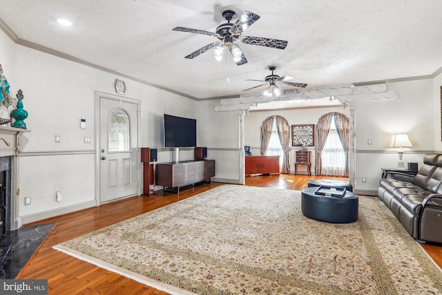 living room with crown molding, ceiling fan, hardwood / wood-style floors, and a textured ceiling