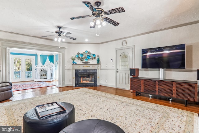 living room with ceiling fan, french doors, a textured ceiling, hardwood / wood-style flooring, and crown molding