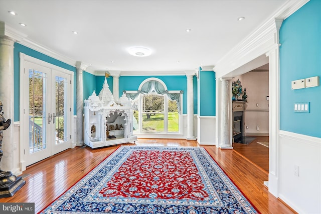 interior space featuring ornamental molding, decorative columns, french doors, and wood-type flooring