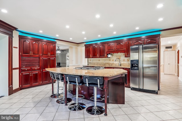 kitchen featuring ornamental molding, sink, a kitchen island, stainless steel appliances, and a breakfast bar area