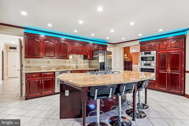 kitchen with sink, ornamental molding, stainless steel appliances, a center island, and a breakfast bar area