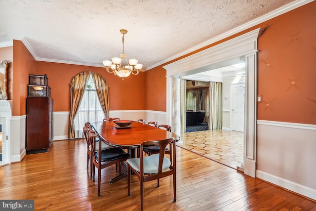 dining space featuring wood-type flooring, crown molding, a notable chandelier, and a textured ceiling