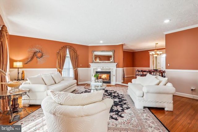 living room featuring a premium fireplace, crown molding, hardwood / wood-style floors, and a chandelier