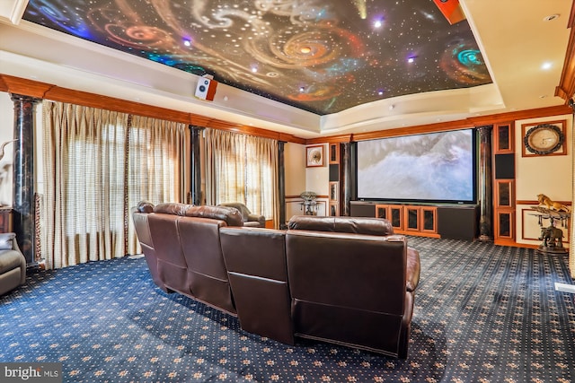 carpeted home theater featuring a raised ceiling and crown molding