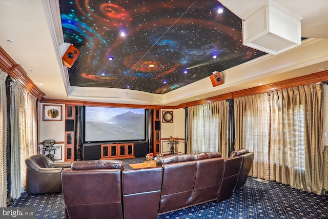 cinema room with ornamental molding, carpet flooring, and a raised ceiling