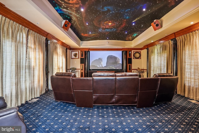 carpeted home theater room with crown molding and a raised ceiling