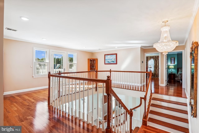 hall featuring ornamental molding, hardwood / wood-style floors, and an inviting chandelier