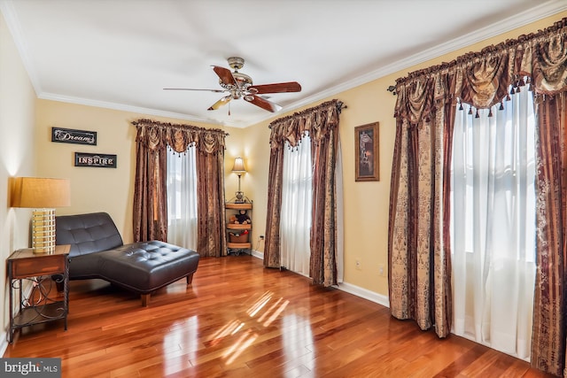 living area with crown molding, hardwood / wood-style flooring, and ceiling fan