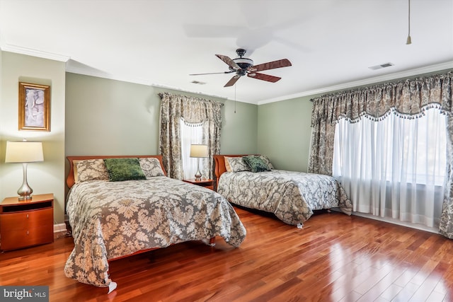 bedroom with crown molding, hardwood / wood-style floors, multiple windows, and ceiling fan