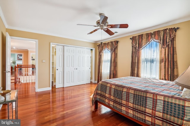 bedroom with hardwood / wood-style flooring, crown molding, ceiling fan, and a closet