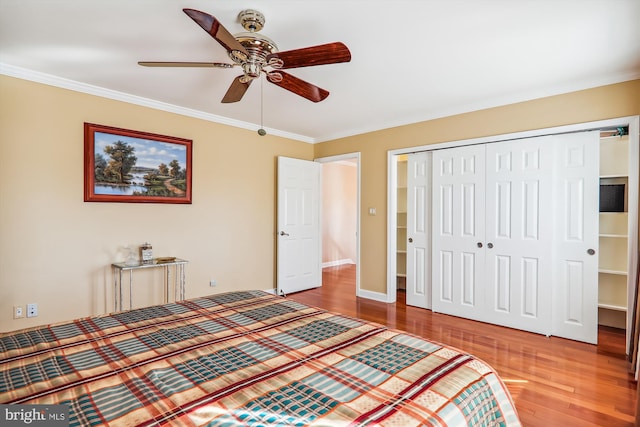 unfurnished bedroom featuring a closet, crown molding, hardwood / wood-style flooring, and ceiling fan